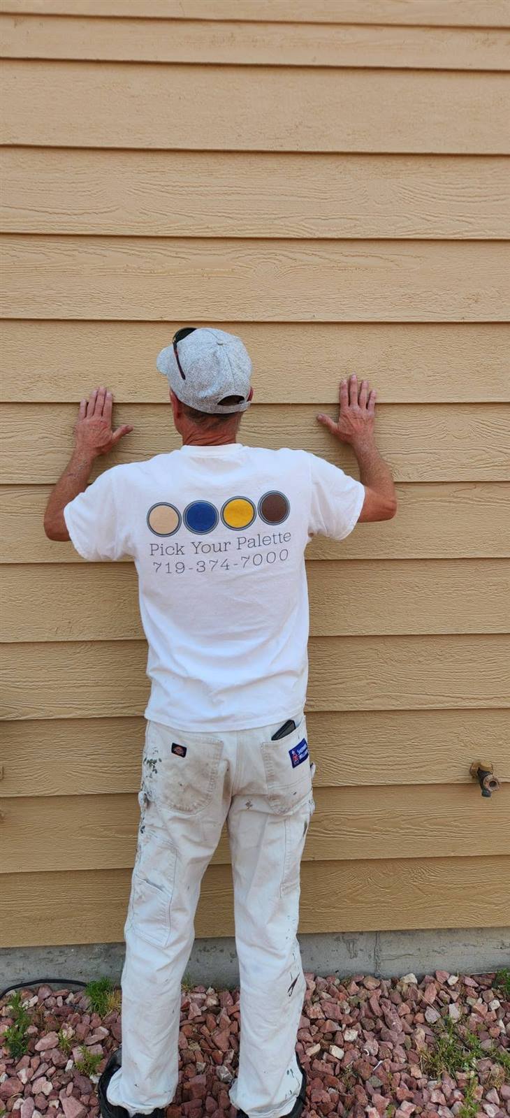 Pick Your Palette painter in a branded shirt working on exterior siding